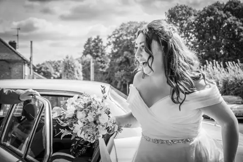Bride looks over the moon to be arriving from her classic wedding car