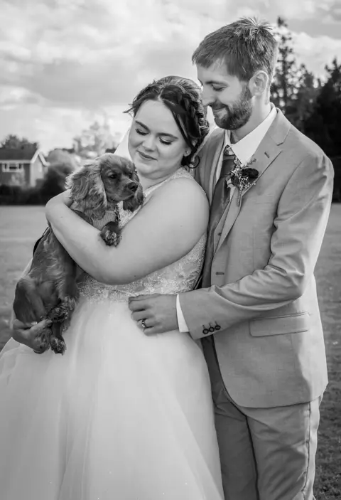 The bride and groom celebrate their wedding with their puppy