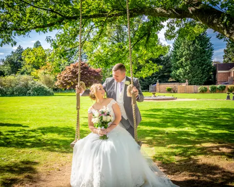 The groom pushes the bride on a swing